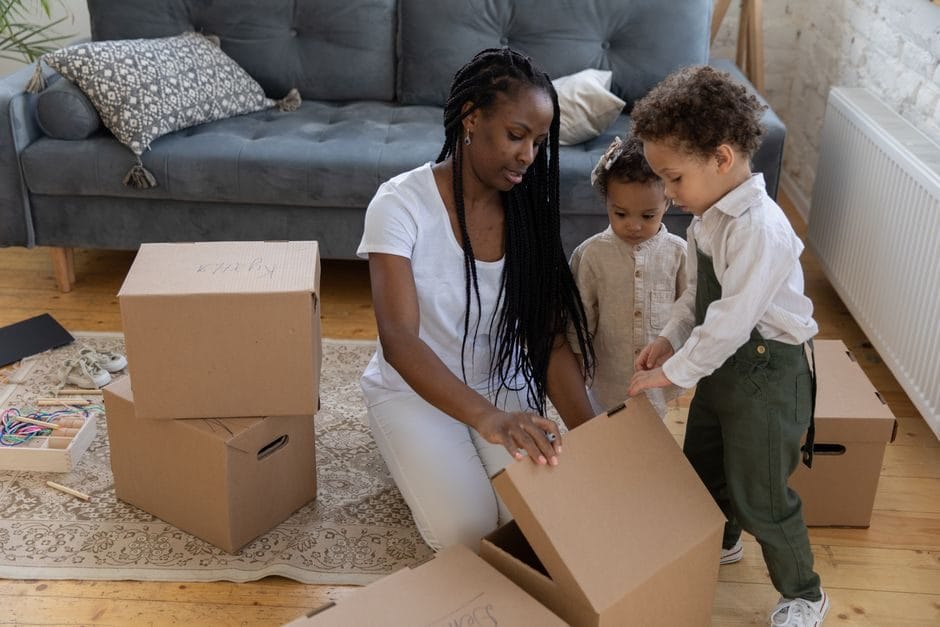 Dos niños jugando con cajas de cartón en el salón de casa en verano